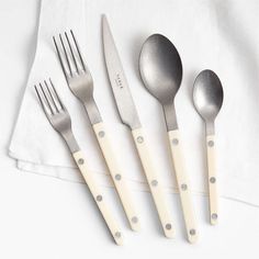 four forks, two spoons and one knife on a white napkin with silver dots