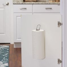 a roll of toilet paper is hanging on the wall in front of an open refrigerator