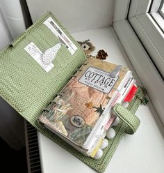 an open book sitting on top of a white table next to a window sill