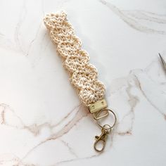 a crocheted keychain on a marble surface with scissors and yarn in the background