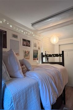 a bedroom with white bedding and pictures on the wall