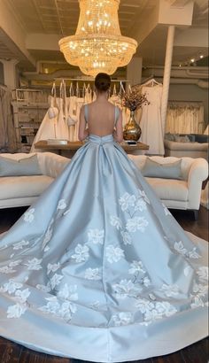 a woman standing in front of a couch wearing a blue dress with white flowers on it