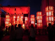 people are standing around in front of some red lanterns at night, with lights on them