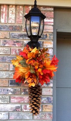 a pine cone hanging from the side of a brick building with autumn leaves on it