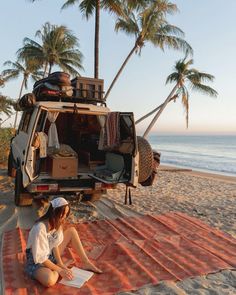 a woman sitting on top of a blanket next to an suv