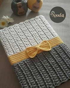 there is a crocheted book with a yellow bow on it and two balls of yarn next to it