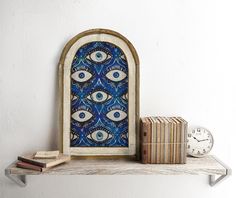 there is a shelf with books and an eye shaped window on it next to a clock