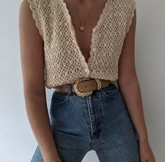 a woman wearing jeans and a crochet top is posing for the camera with her hands in her pockets