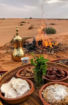 desert food is served in clay bowls on a table near a fire pit and potted plant