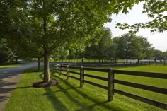 a fenced in area next to a road with trees and grass on both sides