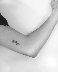 a black and white photo of a woman's arm with a rose tattoo on it