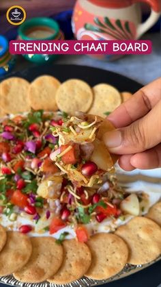 a person dipping some crackers into a bowl of food on top of a plate