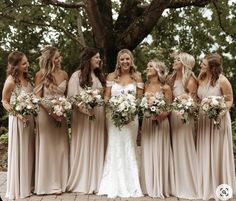 a group of women standing next to each other in front of a tree with flowers