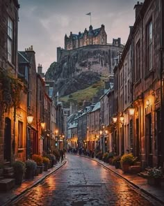 an empty street in the middle of a city with buildings on both sides and a castle at the top