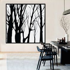 a dining room table with black chairs and a painting on the wall above it that has trees painted on it