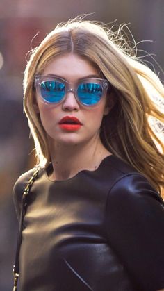 a woman wearing blue sunglasses walking down the street