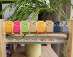 colorful lego blocks sitting on top of a wooden shelf next to a potted plant