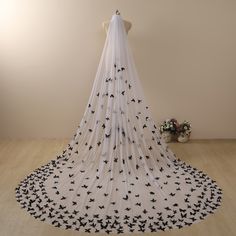 a white veil with black birds on it and flowers in the corner next to it