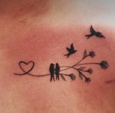 a woman's chest with two birds on it and one bird sitting on the branch