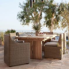 an outdoor dining table with chairs and a potted plant on the outside patio area