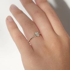 a woman's hand with a diamond ring on top of her left hand,