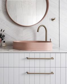 a bathroom sink with a round mirror above it and two brass handles on the side