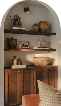 a living room with shelves and vases on top of the shelf, along with a chair