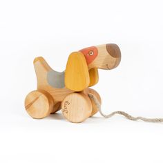 a wooden toy dog sitting on top of a white floor next to a string attached to it