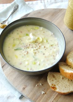 a bowl of soup and some bread on a cutting board