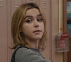 a woman with blonde hair is standing in front of lockers and looking off to the side