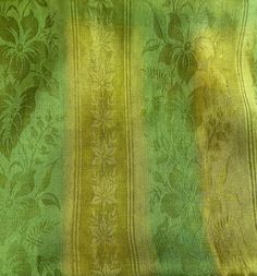 a green and yellow striped fabric with flowers on the side, as well as leaves