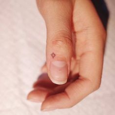 a person's finger with a tiny flower tattoo on it