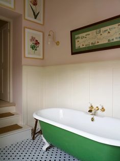 a green and white bath tub sitting in a bathroom next to stairs with pictures on the wall