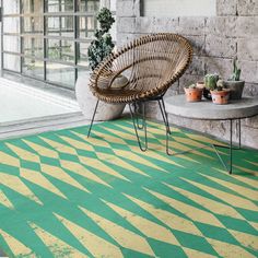 a room with a chair, potted plants and a rug on the floor in front of a brick wall