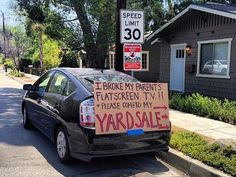 a car parked in front of a house with a yard sale sign attached to it