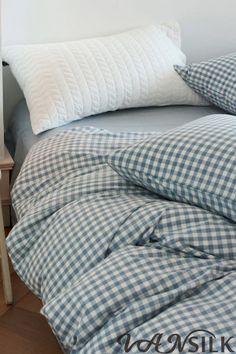 an unmade bed with blue and white checkered sheets