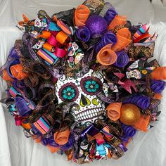 a wreath made out of colorful hair bows and skulls on a white sheeted surface