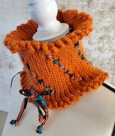 an orange knitted cowgirl's sweater on a mannequin headdress