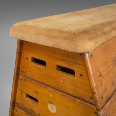 an old wooden chest with two drawers and a cushion on the top, against a gray background