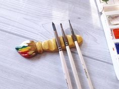 three paintbrushes are sitting on the table next to some art supplies