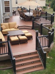 an outdoor deck with seating and stairs leading to a patio area that is surrounded by lawn furniture