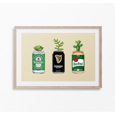 three beer cans with plants growing out of them in front of a white wall mounted on a wooden frame