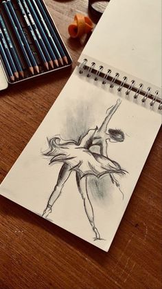 a pencil drawing of a ballerina on a table next to some crayons