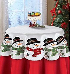 a christmas table cloth with snowmen on it and a tree in the background,