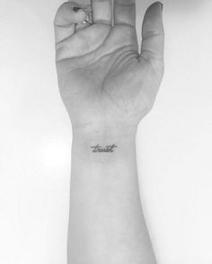 a woman's hand with a small tattoo on the wrist that says, trust