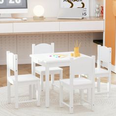 a white table and chairs are in front of a computer desk with a clock on the wall