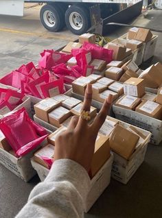 a person pointing at boxes on the ground with pink ribbon wrapped around them and someone's hand