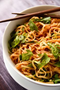 a white bowl filled with noodles and greens