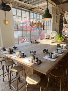 an empty restaurant with wooden tables and stools in front of large windows, overlooking the street