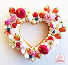 a heart shaped wreath made with flowers and strawberries in the shape of a heart